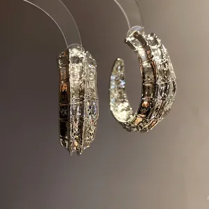 Primer plano detallado de pendientes en forma de C plateados con una textura martillada