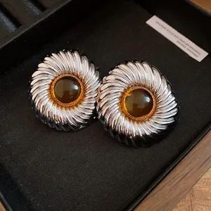 Close-up detail of vintage-style ridged silver stud earrings with central amber resin cabochons