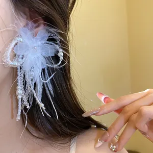 Vista dettagliata di un elegante orecchino a fiori con piume bianche e perle su una modella