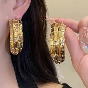 Primer plano de pendientes de aro dorados en forma de C con un acabado de textura arrugada