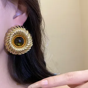 Close-up detail shot of elegant gold textured round stud earring with resin center on ear