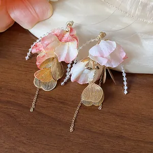 Close-up of elegant acrylic flower petal earrings with golden leaf charms and beaded strands
