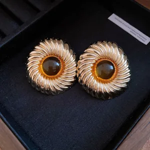 Close-up detail of elegant vintage gold swirling stud earrings with deep resin center stone
