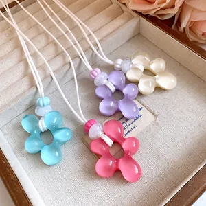 Set di quattro collane con ciondolo a fiore in resina colorata con cordoncino bianco.