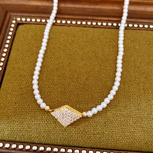 Close-up detail of a white pearl necklace with a sparkling zircon rhombus pendant.