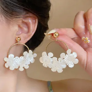 Gros plan de boucles d'oreilles créoles fleurs en cuir blanc style français élégant