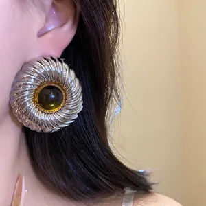Detailed macro view of textured silver round stud earring with dark amber resin center