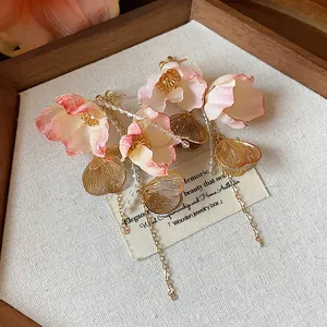 Detailed close-up of elegant pink acrylic flower dangle earrings with gold chains
