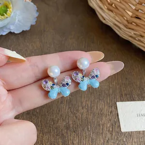 Detail view of colorful zircon butterfly earrings with pearl studs on a blue wing base.