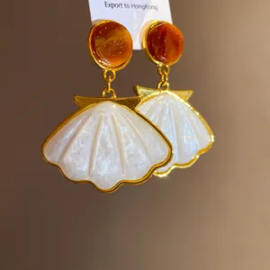 Macro view showing the detailed shell texture of vintage resin pendant earrings.