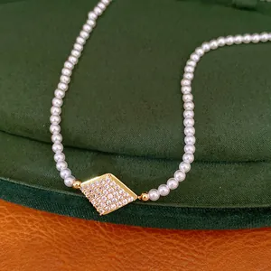 Close-up view of elegant 18K gold plated pearl necklace with a sparkling diamond-shaped CZ pendant