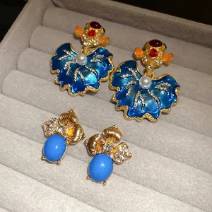 Vintage enameled leaf earrings with gold fish and rhinestone accents in jewelry tray.