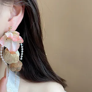 Detailed view of elegant acrylic petal earrings with golden shell charms and beads.