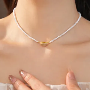 Close-up detail of a white pearl necklace with a gold zircon geometric pendant