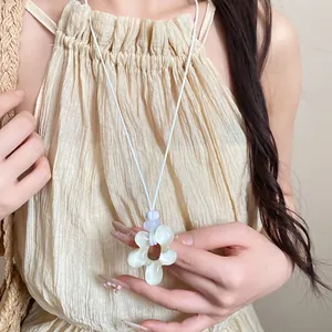 Primo piano di una collana con ciondolo a fiore in resina irregolare dal tocco dolce