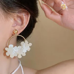 Détail de boucles d'oreilles créoles de style français avec fleurs en cuir blanc