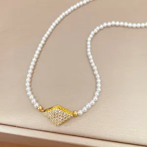 Close-up of geometric diamond pendant with pavé zircon on elegant pearl choker necklace