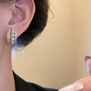 Nahaufnahme eines eleganten vergoldeten Ohrclips mit Perlen und schimmernden Zirkonen