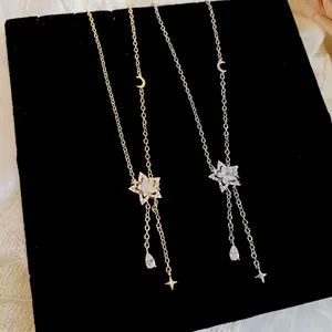 Elegant zirconia star and moon tassel necklace in gold and silver finish on black velvet.