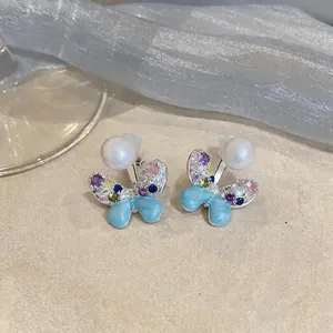 Detailed macro shot of butterfly stud earrings with pearls and colorful zircons