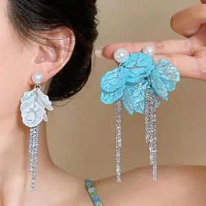 Detailed view of elegant pearl earrings featuring blue and white petals and tassels.