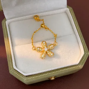 Detailed close-up of a golden chain ring with a sparkling flower charm in a gift box