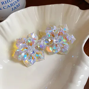 Gros plan de boucles d'oreilles fleurs en verre irisé sur un plateau coquillage blanc