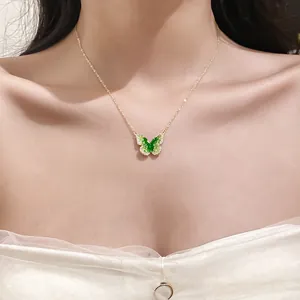 Detail view of dainty gold chain necklace with a green crystal butterfly pendant
