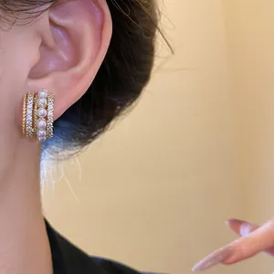 Nahaufnahme eleganter 14k vergoldeter Ohrringe mit Perlen und Zirkonia am Ohr