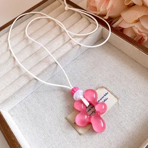 Vista dettagliata della collana con ciondolo a fiore in resina rosa e cordino in pelle bianca