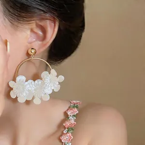 Gros plan de boucles d'oreilles créoles avec fleurs en cuir blanc de style français
