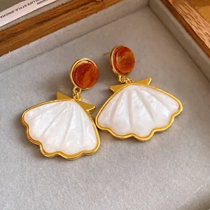 Macro view of French retro shell pendant earrings with golden finish in jewelry tray