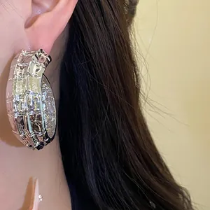 Primer plano de pendientes de aro en C plateados plisados con textura vintage elegante