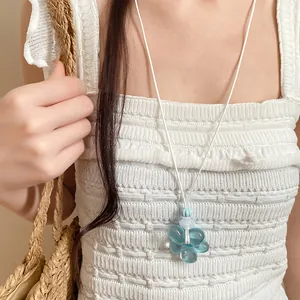 Dettaglio di una collana con ciondolo a fiore in resina azzurra e cordino in pelle bianca