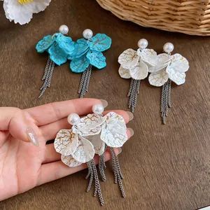 Macro detail of elegant petal tassel earrings with artificial pearls and gold texture
