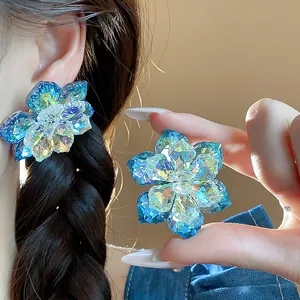 Gros plan sur des boucles d'oreilles fleur en cristal bleu aux reflets irisés et brillants