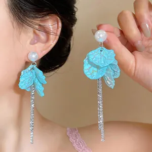 Detail view of light blue petal tassel earrings with white pearls and sparkling silver chains