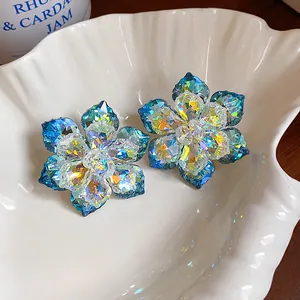 Détail macro de boucles d'oreilles fleurs en verre irisé dans un plat en coquillage blanc