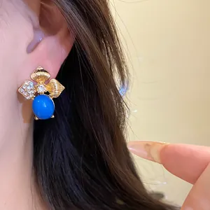 Close-up detail of vintage leaf earring with blue stone and rhinestones on ear