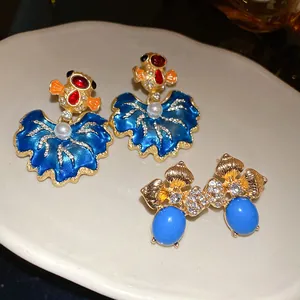 Detailed view of vintage gold-tone earrings with blue enamel leaves and stones.