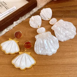 Close-up detail of vintage resin shell pendant earrings featuring elegant white pearls.
