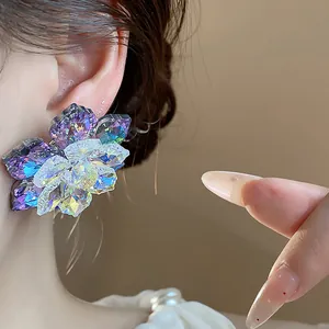 Gros plan de boucles d'oreilles fleurs en verre iridescent avec détails en cristal facetté.