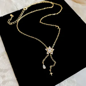 Detailed close-up of gold star necklace with sparkling zircon teardrop tassel pendant.