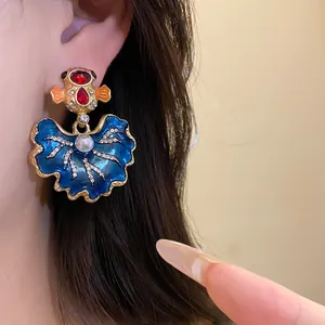 Detailed view of vintage style blue enamel leaf earrings with rhinestones and pearl inlay.
