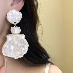 Close-up of vintage resin shell pendant earring with pearl-like luster worn on ear