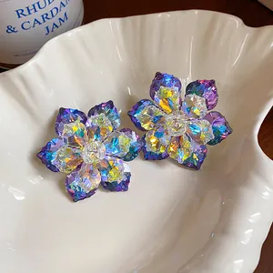 Détail de boucles d'oreilles fleurs en verre irisé dans une coupelle en coquillage
