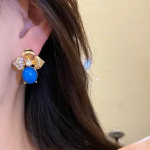 Elegant close-up shot of vintage gold leaf earring featuring blue enamel and rhinestones