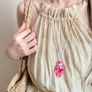 Dettaglio di una collana con ciondolo a fiore in resina rosa e cordino bianco