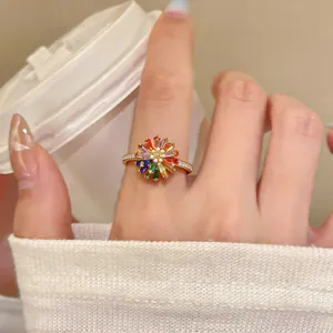 Detail of an 18k gold plated flower ring with colorful zirconia stones worn on a finger.