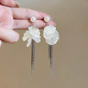 Detailed view of pearl stud earrings with shell-like flower petals and silver tassels